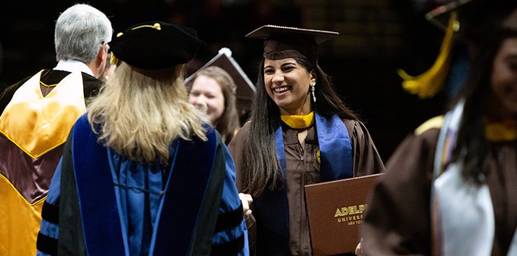  graduate joyfully shaking hands during commencement