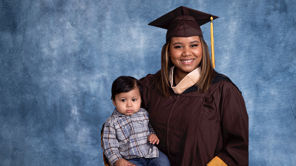 Martinez in her cap and gown, holding her son, Kairo.